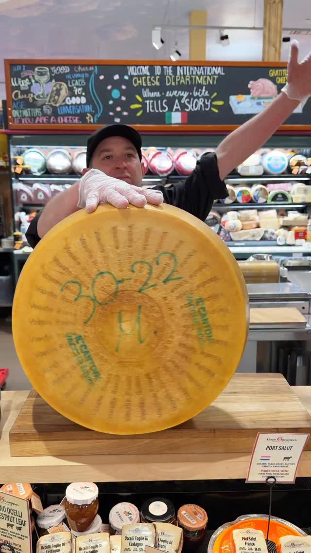 An Uncle Giuseppe's cheese artisan presenting a wheel of aged cheese