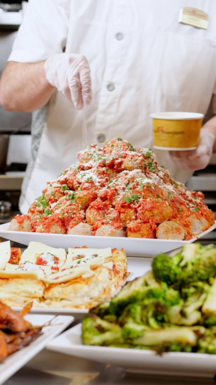 An Uncle Giuseppe's chef finishing a colorful prepared-food display